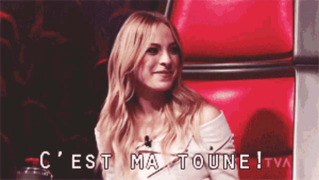 a woman sitting in a red chair with the words c ' est ma toune tva