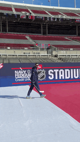a man with a hockey stick is walking on a red carpet in front of a sign that says nhl stadium