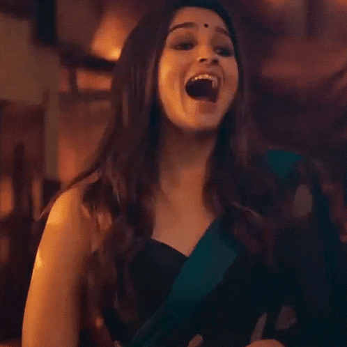 a woman in a black top is making a funny face with her mouth wide open .