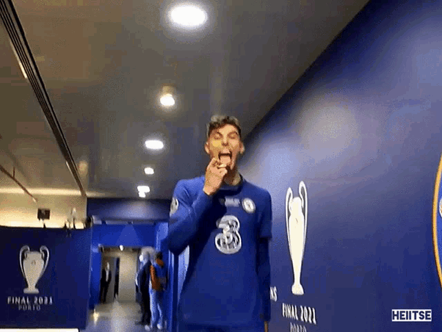 a man in a blue shirt with the number 3 on it is standing in a hallway .