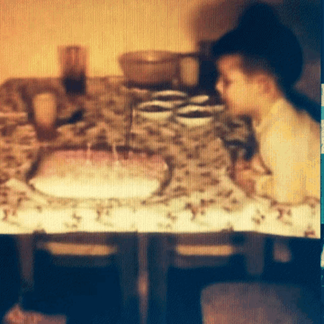 a blurry photo of a child sitting at a table with a cake on it