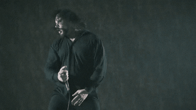 a man in a black shirt is holding a knife in his right hand