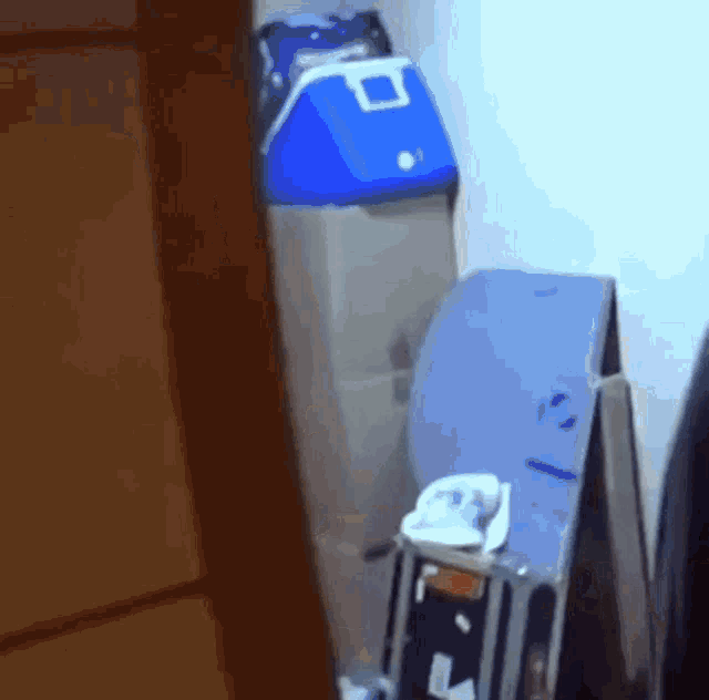 a blue cooler sits on top of a shelf next to a toilet