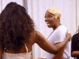 two women are hugging each other while standing next to each other in a room .