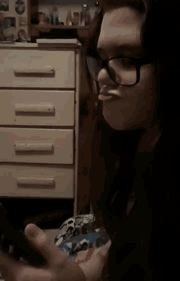 a girl wearing glasses is sitting in front of a white dresser