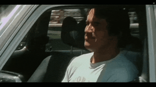 a man in a white shirt is sitting in the back seat of a car