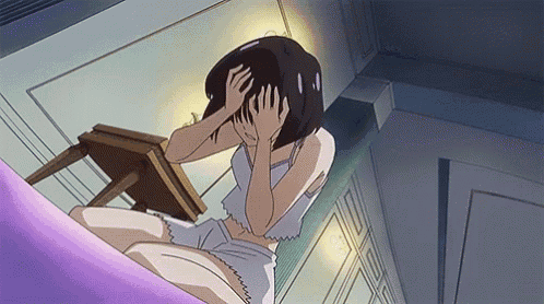 a girl is covering her face with her hands while sitting on a bed .