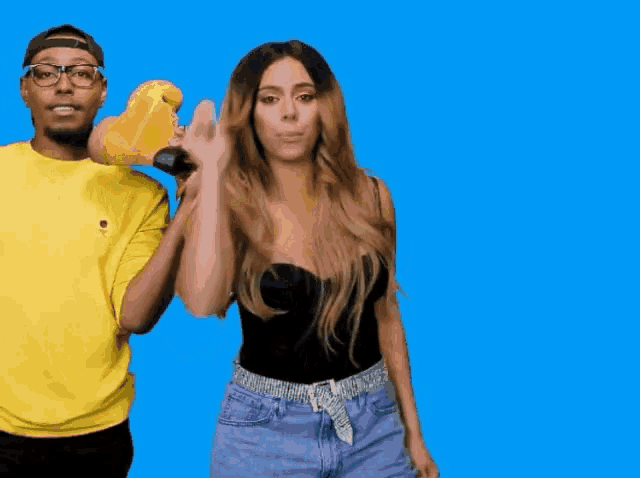 a man in a yellow shirt is holding a skateboard and a woman in a black top is waving