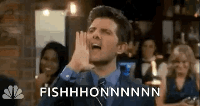 a man in a suit and tie is making a funny face while holding his hands to his face .