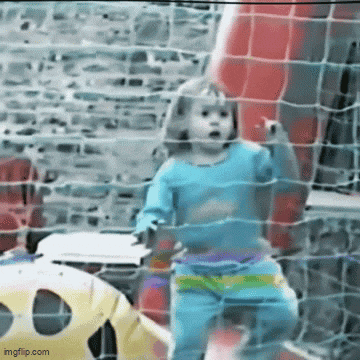 a little girl in a blue shirt is behind a soccer net