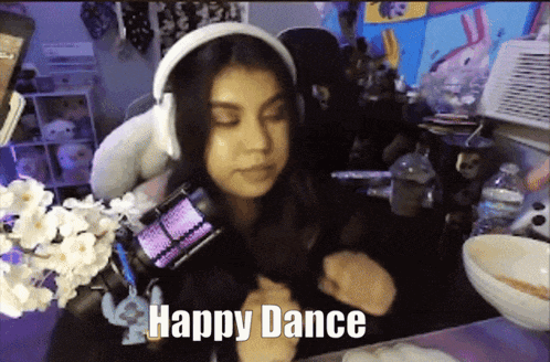 a woman wearing headphones says " happy dance " while dancing