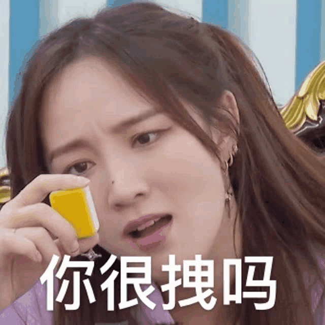a woman is holding a yellow cube and making a funny face .