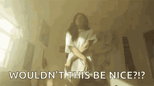 a woman is standing in a room with her arms crossed and says `` wouldn t this be nice ? ''