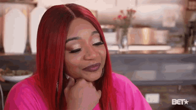 a woman with red hair is wearing a pink shirt with bet on the bottom