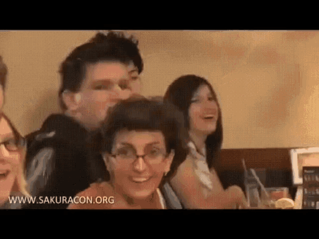 a group of people are sitting at a table in a restaurant laughing .
