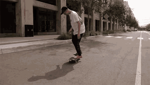 a man is riding a skateboard down a street with graffiti on the side