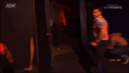 a couple of men are standing next to each other in a dark room with the aew logo on the bottom