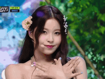a girl with a flower in her hair and a sign that says nmixx on it