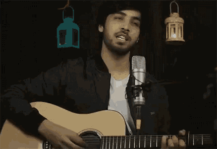 a man is playing an acoustic guitar in front of a microphone .