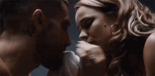 a man and a woman are kissing each other and the woman is holding a feather in her hand .