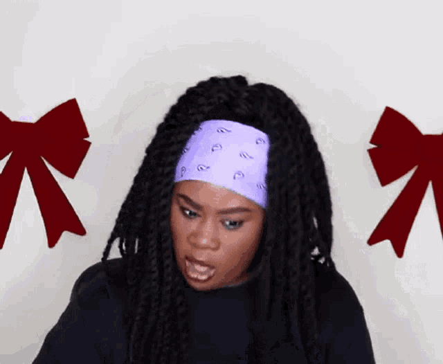 a woman with dreadlocks wearing a purple bandana with the letter p on it