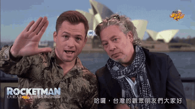 two men are standing next to each other in front of a sign that says rocketman on it
