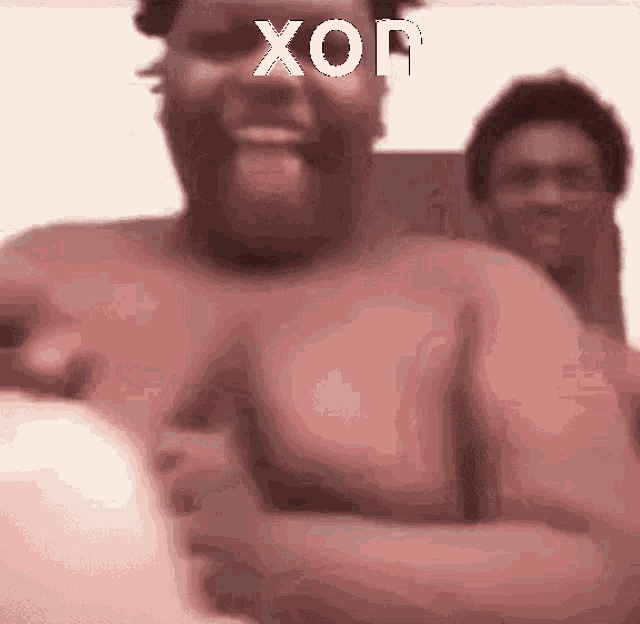 a shirtless man is smiling with the word xon written on his face