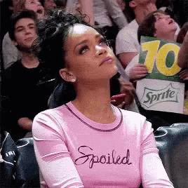 a woman wearing a pink shirt that says spoiled looks up