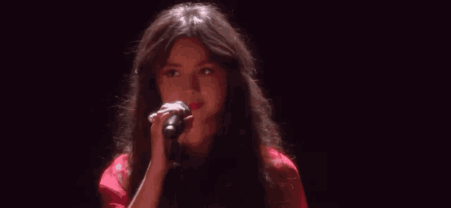 a woman in a red dress is singing into a microphone on a stage .