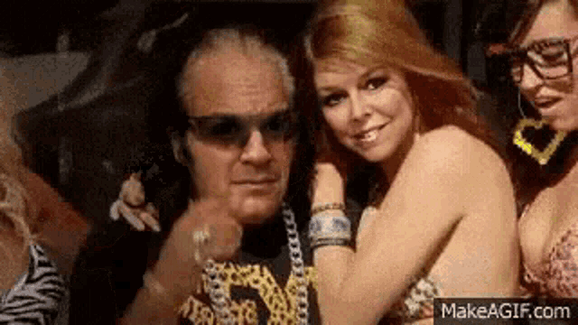 a group of women are posing for a picture with a man in a leopard print shirt .