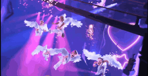 a group of angels are flying through the air in a purple light