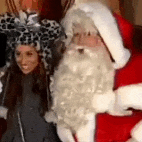 a woman in a leopard print hat is standing next to a santa claus costume .