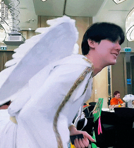a man in a white angel costume is smiling in a room
