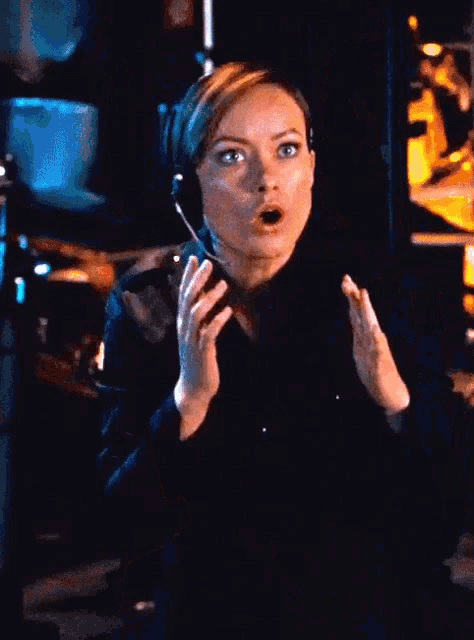 a woman wearing a headset looks surprised in front of a sign that says recovery