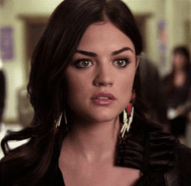 a close up of a woman 's face wearing earrings and a black top