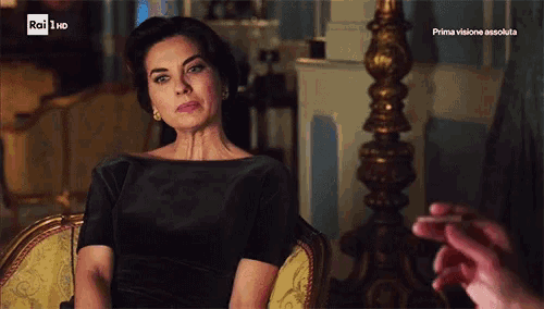 a woman in a black dress sits in a chair in front of a tv screen that says rai hd