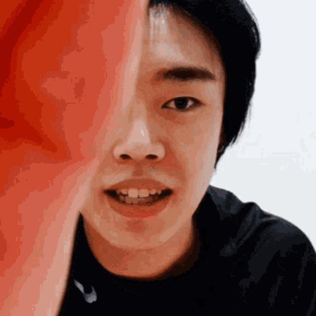 a close up of a young man 's face with a red boxing glove behind him .