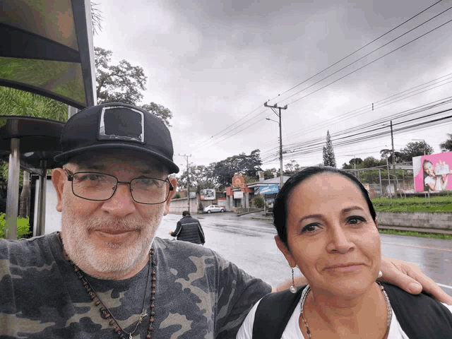 a man and a woman are posing for a picture in front of a billboard that says ' coca cola '