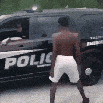a man is dancing in front of a police car