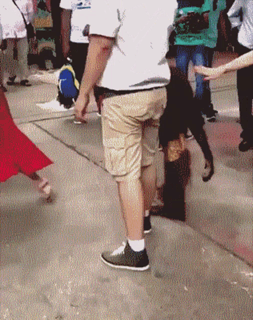 a man wearing khaki shorts and black shoes stands in a crowd of people