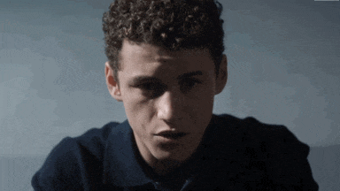 a young man with curly hair wearing a blue shirt