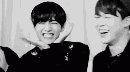 a black and white photo of two young men laughing .