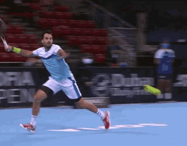 a man is playing tennis on a court with a sign that says dubai on it