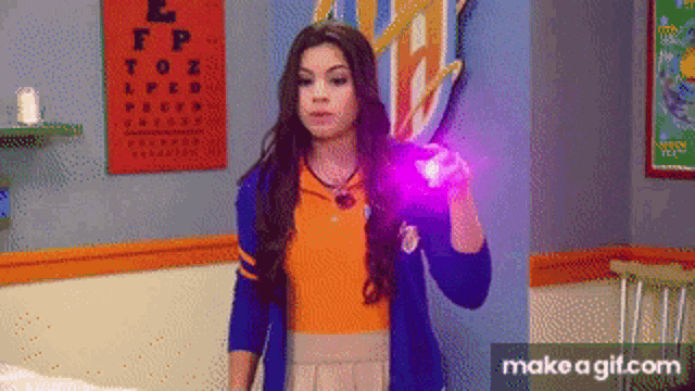 a girl is holding a purple object in front of an eye chart with the letter l on it