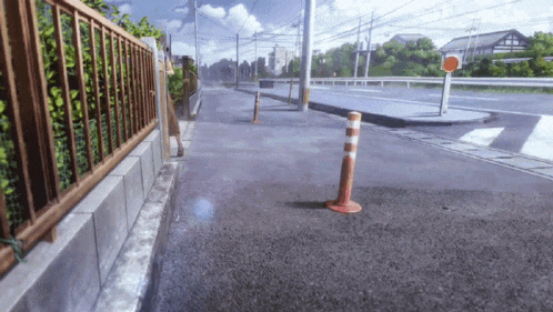 a fence along the side of a road with a red and white pole in the middle