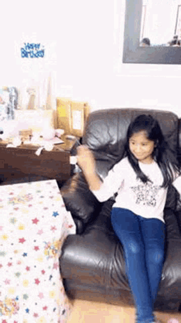 a little girl is sitting on a couch in a living room .