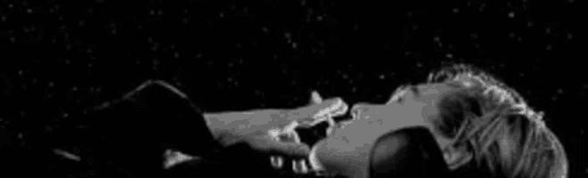 a black and white photo of a woman smoking a cigarette in the dark .