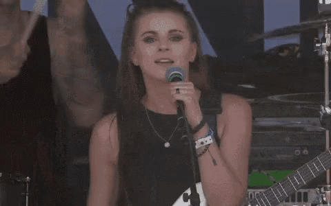 a woman is sitting on a man 's shoulders on a stage in front of a microphone .