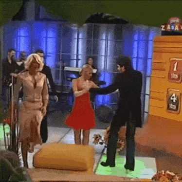 a woman in a red dress is standing next to a man in a black suit in front of a yellow wall with the number 1 on it