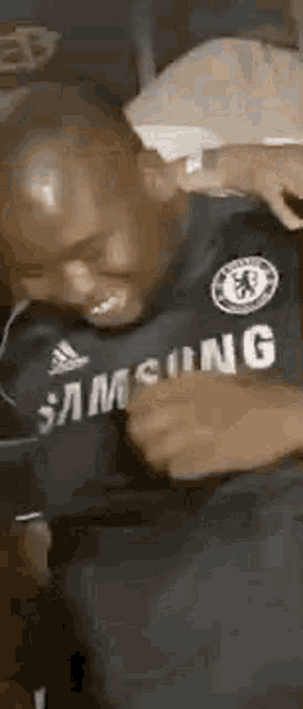 a man wearing a samsung shirt is dancing in a bedroom .